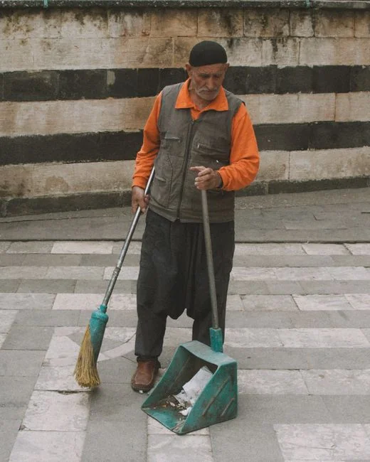 Side view of young ethnic male in uniform cleaning floor with mop while working in retro styled restaurant